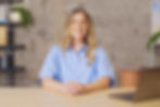 The female presenter for the Wix Studio Essentials course sitting facing the camera at a desk with a MacBook on it.